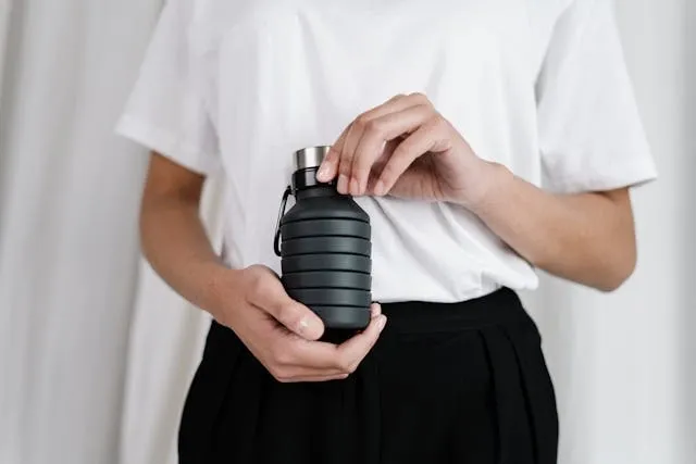 a person wearing a white shirt holding a black water bottle for how many ounces in a water bottle